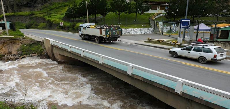 Carros transitando encima de un puente que pasa por el río.