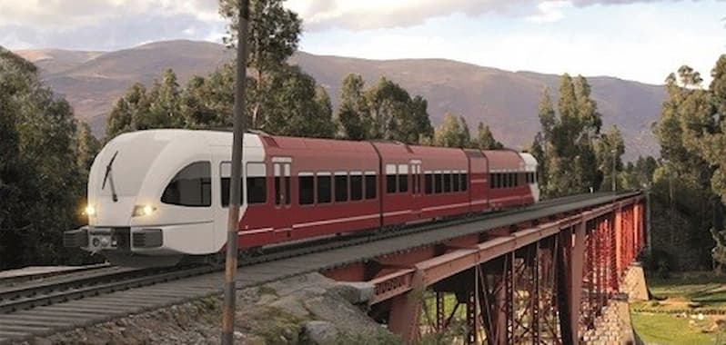 Un moderno tren de color rojo y blanco cruza un puente ferroviario de estructura metálica en un paisaje natural rodeado de árboles y montañas.