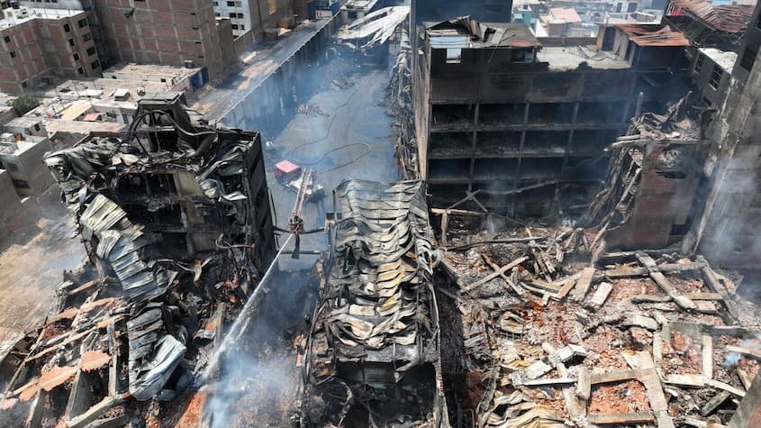 Imagen aérea de un conjunto de edificaciones gravemente afectadas por un incendio en una zona urbana. Los edificios están parcialmente colapsados, con techos retorcidos y estructuras destruidas.