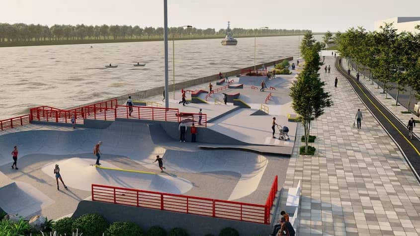 La imagen muestra el diseño de un skatepark ubicado junto al río en Barranquilla. Se trata de un espacio moderno con diversas rampas y obstáculos para la práctica del skateboarding, patinaje y BMX, rodeado de una vía peatonal y ciclovía con áreas verdes.