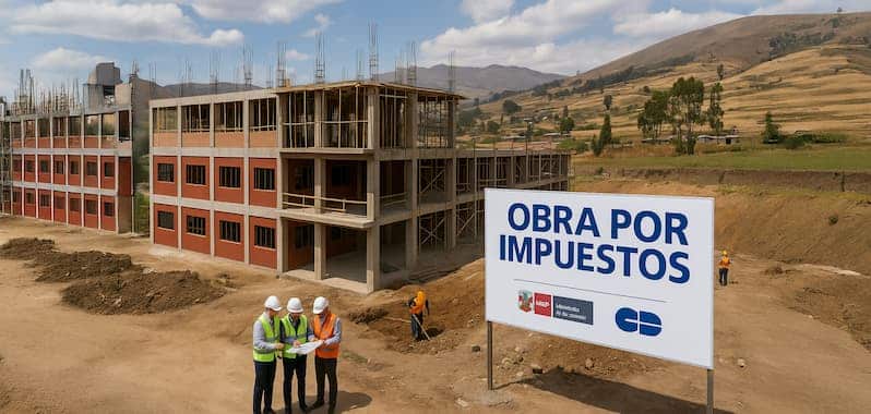 Construcción de infraestructura educativa en zona rural del Perú, realizada bajo el mecanismo de Obras por Impuestos. Se observa un edificio de varios niveles en etapa estructural, trabajadores con cascos y chalecos, y un cartel institucional que indica la modalidad del proyecto con logos del gobierno y empresa privada.