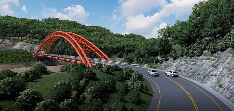 Representación digital de un puente vehicular con arco metálico rojo que cruza un valle rodeado de vegetación densa. La carretera de doble sentido se curva suavemente antes de llegar al puente, con dos vehículos blancos circulando en dirección opuesta. El paisaje es montañoso, con árboles frondosos y un cielo parcialmente nublado.