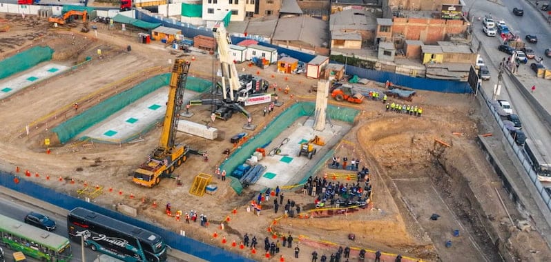 Construcción del bypass Las Torres en Lima con maquinaria pesada, cimentaciones profundas y presencia de autoridades durante inspección de obra vial.