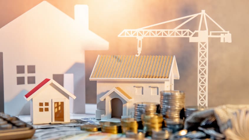 Ilustración sobre el retiro AFP construcción, con maquetas de viviendas, grúa y monedas que simbolizan inversión inmobiliaria en Perú.