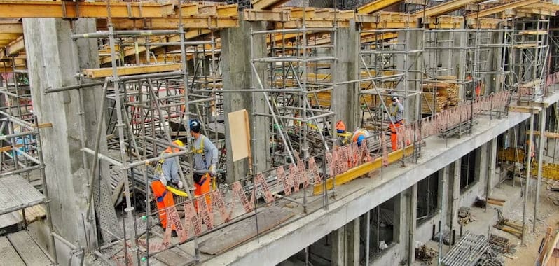 Trabajadores supervisan labores de construcción en terreno urbano, asegurando el correcto avance y calidad de la obra civil.