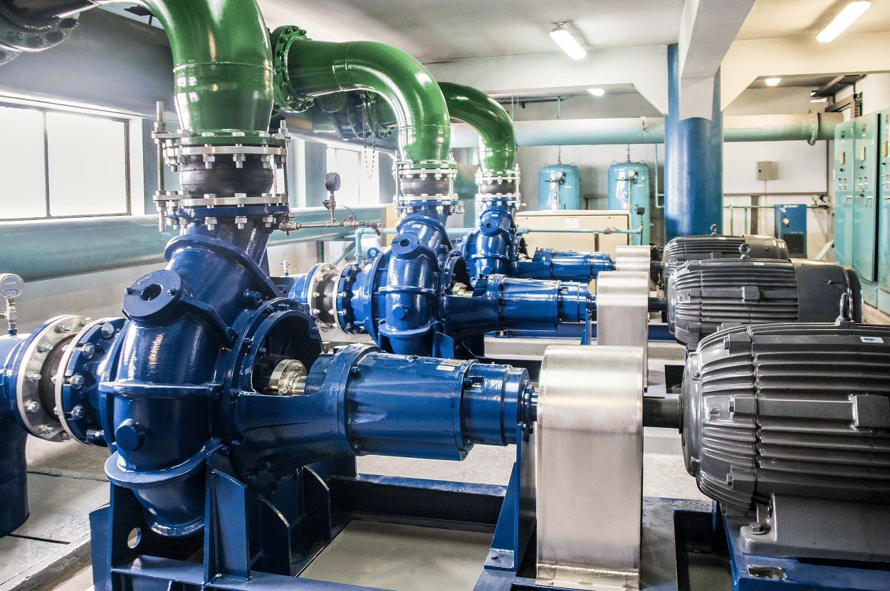 “Sala de bombas industriales con tuberías verdes y equipos electromecánicos azules utilizados para el manejo de agua o fluidos en planta de tratamiento o infraestructura industrial.”