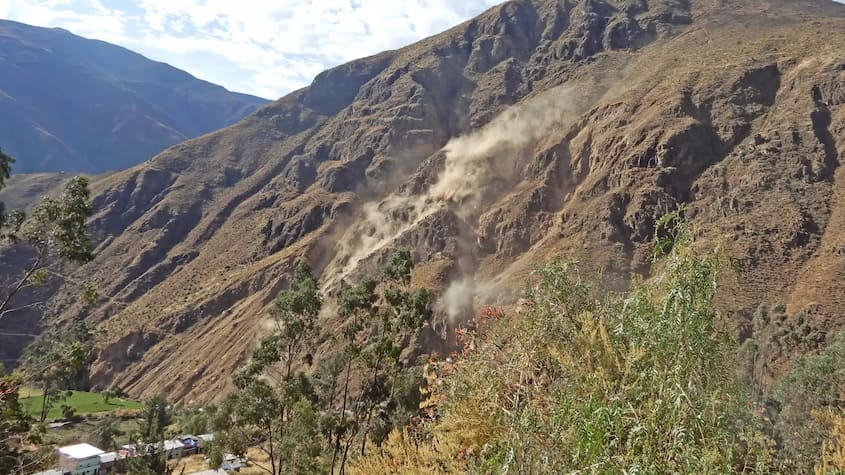Deslizamiento de rocas en ladera andina con nube de polvo, alerta por peligros geológicos que afectan obras e infraestructura