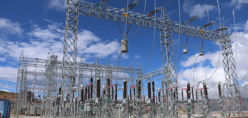 Ingenieros inspeccionan subestación eléctrica de transmisión, infraestructura clave para proyectos energéticos en expansión.